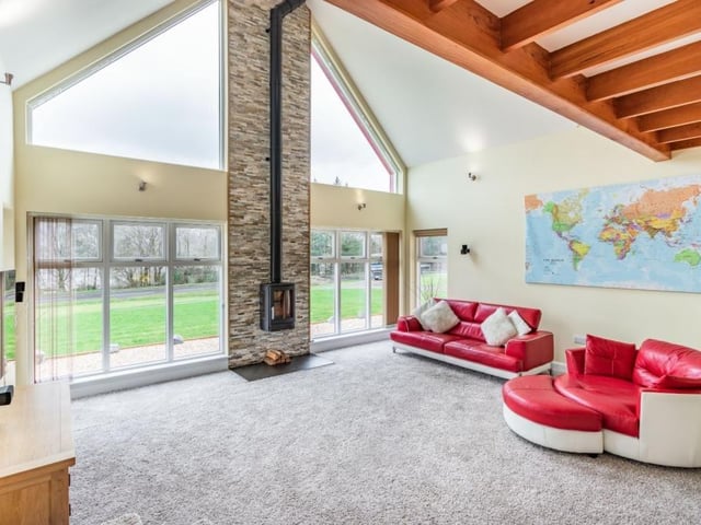 Sitting room with contemporary wood burner flanked on each side by full-height picture windows with stunning views over the loch.