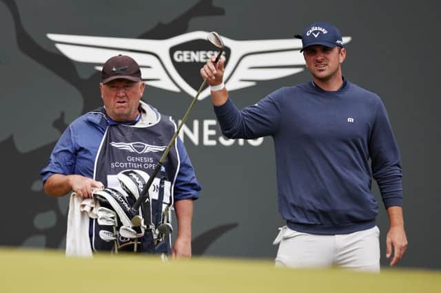 Will Gordon selects a club from his bag as his caddie, Glasgow man Jeffrey Paul, looks on from the 18th green during day one of the Genesis Scottish Open at The Renaissance Club. Picture: Jared C. Tilton/Getty Images.