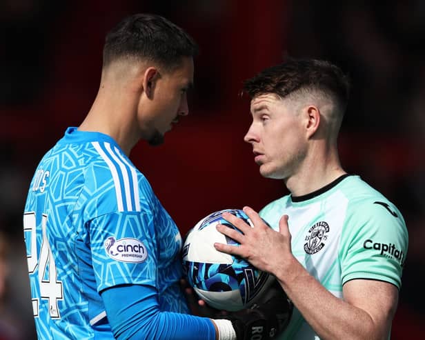 Aberdeen's Kelle Roos (L) speaks with Hibs' Kevin Nisbet (R) before he misses a penalty at Pittodrie.