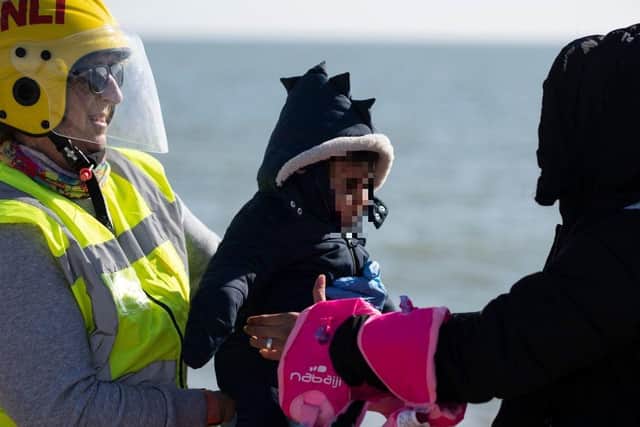 A rescuer gives a baby back to the mother on the beach after disembarking from an RNLI lifeboat, in Dungeness, on the southeast coast of England, last month, after crossing the English Channel.