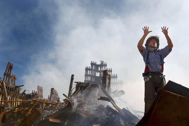 A New York City firefighter calls for ten more rescue workers to make their way into the rubble of the World Trade Center as work continues three days after the attcks (Picture: US Navy photograph by Preston Keres/Getty Images)