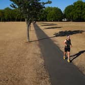 A jogger runs along a path next to sun scorched grass in London's Victoria Park
