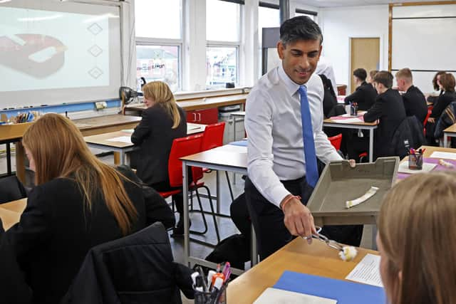 After an experiment in which cigarette smoke was passed through cotton wool, Rishi Sunak passes round the results to children at a school in Boston, Lincolnshire (Picture: Darren Staples/WPA pool/Getty Images)