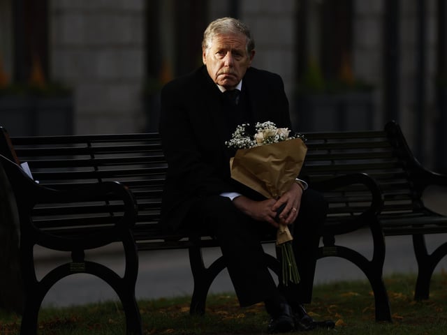 A man looks on from a bench with a bouquet of flowers as he waits to view the cortege  in Ballater (Photo by Jeff J Mitchell/Getty Images)