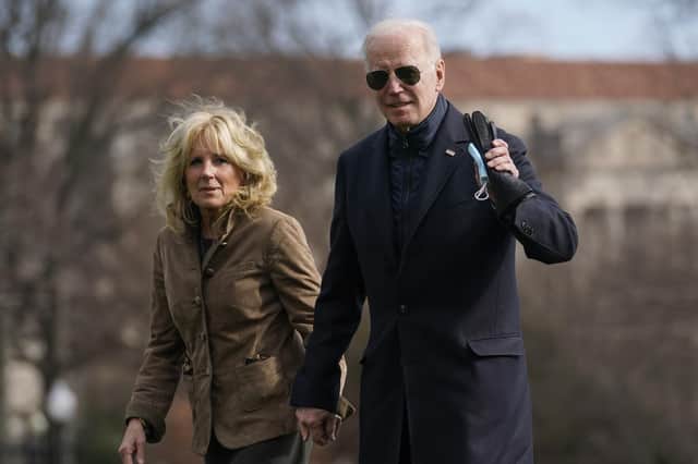 President Joe Biden looks to media as he and and first lady Jill Biden walk across the South Lawn after arriving on Marine One at the White House in Washington, Sunday, March 13, 2022.