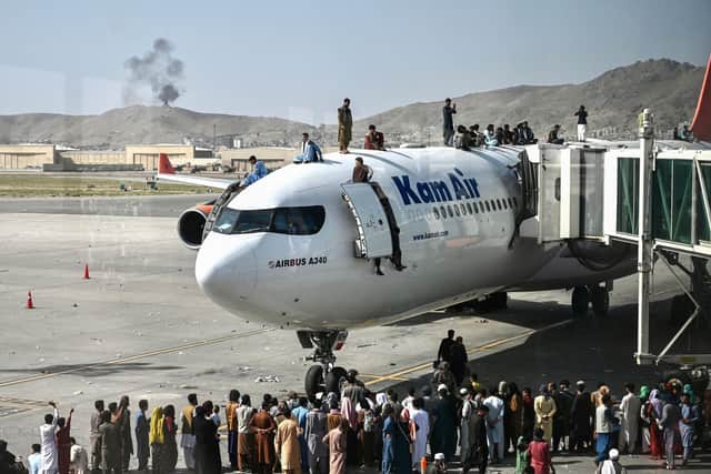 People climb on top of a plane at the Kabul airport in the hope of escaping the Taliban (Picture: Wakil Kohsar/AFP via Getty Images)