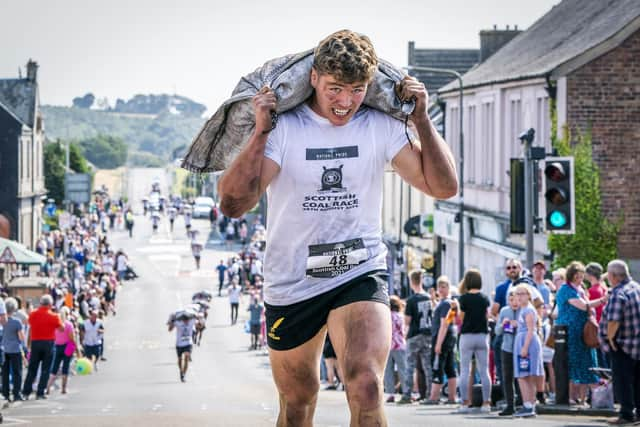 Wallace Nelson, from Kinross, goes on to win the Mens Race in the Scottish Coal Carrying Championships through the streets of Kelty in Fife.  Picture date: Saturday August 28, 2021. PA Photo. The annual event is one of only two Coal Races in the world and the men's race requires participants to carry a 50-kilo bag of coal and the women's race requires a 25-kilo bag of coal to be carried over 1000 metres through the village. Photo credit should read: Jane Barlow/PA Wire 