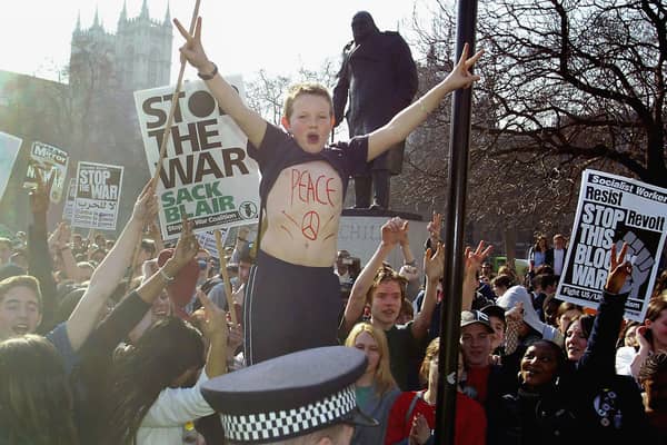 A young protester with 'peace' written on his chest demonstrates outside the Houses of Parliament with military action against Iraq loomng in 2003
