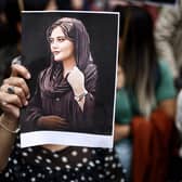 A protester holds a portrait of Mahsa Amini during a demonstration in her support in front of the Iranian embassy in Brussels on September 23, 2022, following the death of an Iranian woman after her arrest by the country's morality police in Tehran. - Mahsa Amini, 22, was on a visit with her family to the Iranian capital Tehran, when she was detained on September 13, 2022, by the police unit responsible for enforcing Iran's strict dress code for women, including the wearing of the headscarf in public. She was declared dead on September 16, 2022 by state television after having spent three days in a coma. (Photo by Kenzo TRIBOUILLARD / AFP) (Photo by KENZO TRIBOUILLARD/AFP via Getty Images)