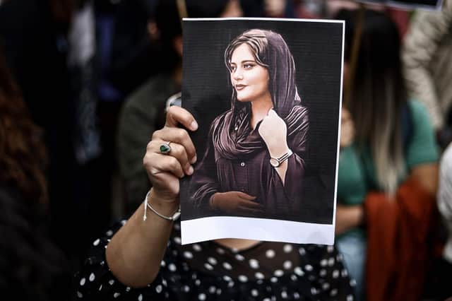 A protester holds a portrait of Mahsa Amini during a demonstration in her support in front of the Iranian embassy in Brussels on September 23, 2022, following the death of an Iranian woman after her arrest by the country's morality police in Tehran. - Mahsa Amini, 22, was on a visit with her family to the Iranian capital Tehran, when she was detained on September 13, 2022, by the police unit responsible for enforcing Iran's strict dress code for women, including the wearing of the headscarf in public. She was declared dead on September 16, 2022 by state television after having spent three days in a coma. (Photo by Kenzo TRIBOUILLARD / AFP) (Photo by KENZO TRIBOUILLARD/AFP via Getty Images)