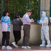 A community volunteer (R) wearing personal protective equipment registers residents before testing for the Covid-19 coronavirus in a compound during a Covid-19 lockdown in Pudong district in Shanghai on April 17, 2022.