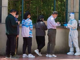 A community volunteer (R) wearing personal protective equipment registers residents before testing for the Covid-19 coronavirus in a compound during a Covid-19 lockdown in Pudong district in Shanghai on April 17, 2022.