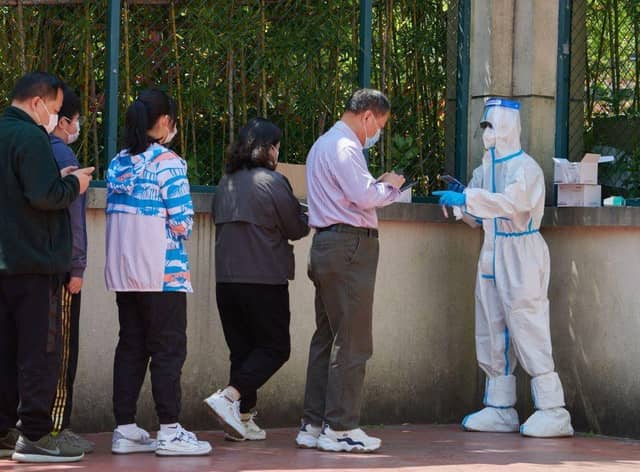 A community volunteer (R) wearing personal protective equipment registers residents before testing for the Covid-19 coronavirus in a compound during a Covid-19 lockdown in Pudong district in Shanghai on April 17, 2022.
