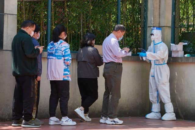 A community volunteer (R) wearing personal protective equipment registers residents before testing for the Covid-19 coronavirus in a compound during a Covid-19 lockdown in Pudong district in Shanghai on April 17, 2022.
