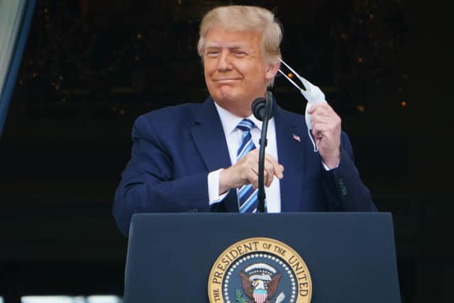 Donald Trump takes his mask off before speaking from the South Portico of the White House during a rally after declaring himself immune from Covid-19 (Picture: Mandel Ngan/AFP via Getty Images)