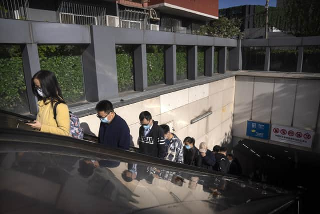 Commuters wearing face masks ride an escalator at a subway station in Beijing, Friday, April 15, 2022. Anti-virus controls that have shut down some of China's biggest cities and fueled public irritation are spreading as infections rise, hurting a weak economy and prompting warnings of possible global shockwaves. (AP Photo/Mark Schiefelbein)