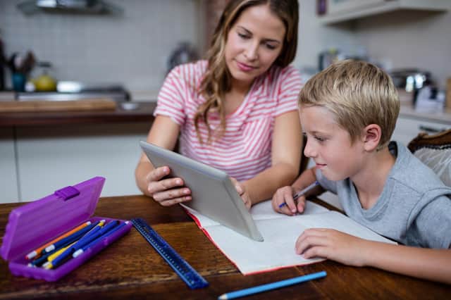 Mother using a digital tablet while helping son with his homework at home