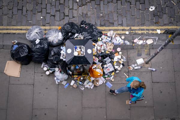 A member of the public walks past a bin and litter in Victoria Street in Edinburgh city centre.