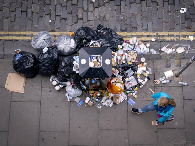 A member of the public walks past a bin and litter in Victoria Street in Edinburgh city centre.