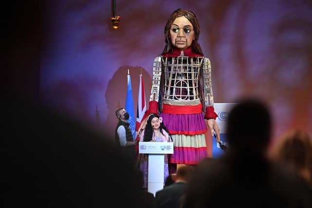 Little Amal, a giant puppet depicting a Syrian refugee girl, arrives on stage as Brianna Fruean, a Samoan member of the Pacific Climate Warriors, delivers a speech during the COP26 UN Climate Change Conference in Glasgow on November 9, 2021(Photo Ben Stansall/AFP via Getty Images).