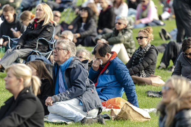 Members of the public watch Queen Elizabeth II's state funeral on a tv screen in Holyrood Park in Edinburgh
