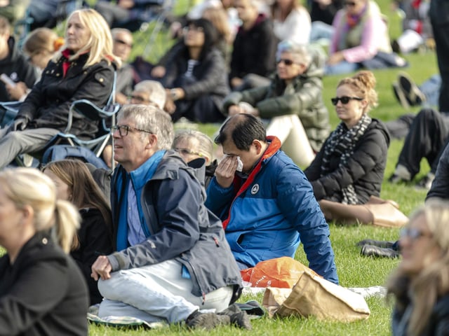 Members of the public watch Queen Elizabeth II's state funeral on a tv screen in Holyrood Park in Edinburgh