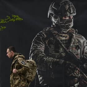 A Ukrainian serviceman walks past a recruiting poster in Kyiv amid the Russian invasion of Ukraine. Picture: Sergei Supinsky/AFP via Getty Images