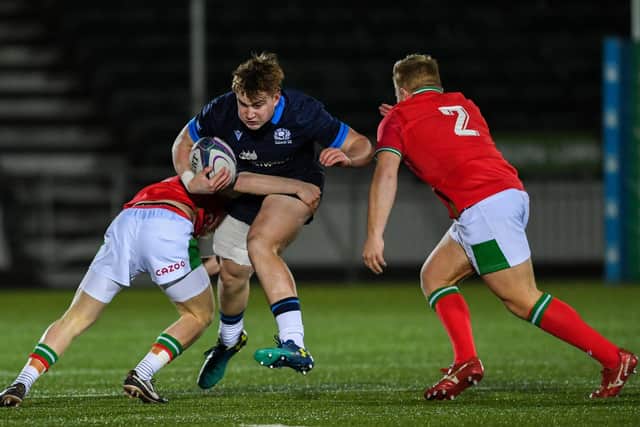 Scotland's Rudi Brown is taken down by two Wales players during the match at Scotstoun.