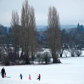 Family play on snow covered hill.