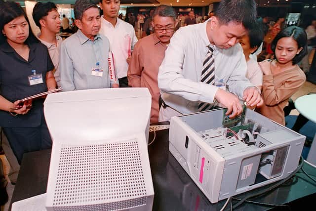 A Filipino technician (2nd R) installs an American-made Cybergeddon PC enhancement card in a computer to demonstrate its features in eliminating the Y2K millennium bug problem, while prospective clients look on at a trade display booth at the international conference on the Y2K problem in Manila 03 March.  Experts from Japan and Hong Kong said their countries were on par with the Western world in putting in place remedies to deal with the Y2K problem in critical sectors of their economies.        AFP  PHOTO/ROMEO GACAD (Photo by ROMEO GACAD / AFP) (Photo by ROMEO GACAD/AFP via Getty Images)