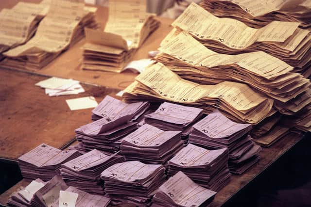 Piles of lilac and peach ballot papers at a Scottish Parliamentary election count.