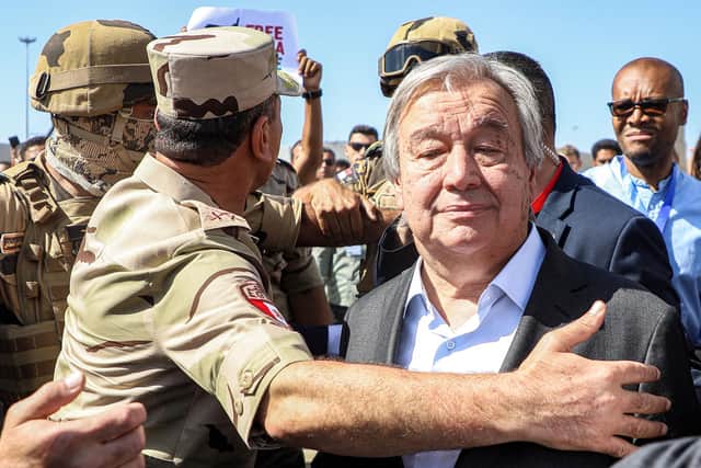 Protesters raise signs in solidarity with Palestinians in the Gaza Strip as Egyptian army officers escort UN Secretary-General Antonio Guterres during his visit to oversee preparations for the delivery of humanitarian aid to the Palestinian enclave on the Egyptian side of the Rafah border last week (Picture: Kerolos Salah/AFP)