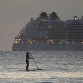 A paddleboarder in the foreground as the Seabourn Ovation cruise ship arrives. Picture: Owen Humphreys/PA Wire