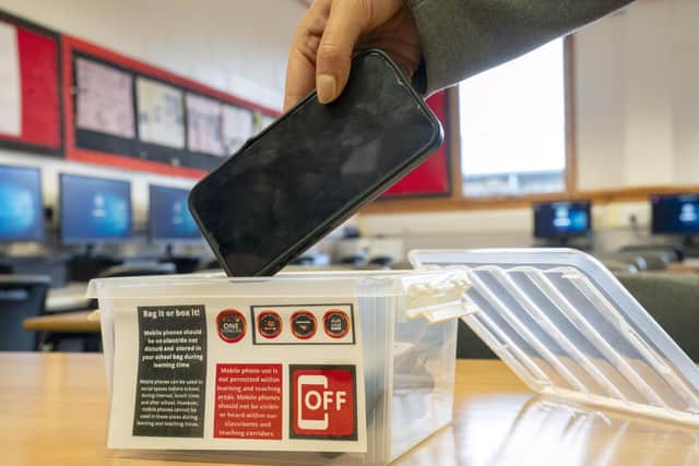 A student places a mobile phone in a box before the start of a lesson. Picture: Jane Barlow/PA Wire