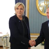 Marine Le Pen shakes hands with Vladimir Putin in 2017, three years after his forces annexed Crimea from Ukraine (Picture: Mikhail Klimentyev/AFP via Getty Images)