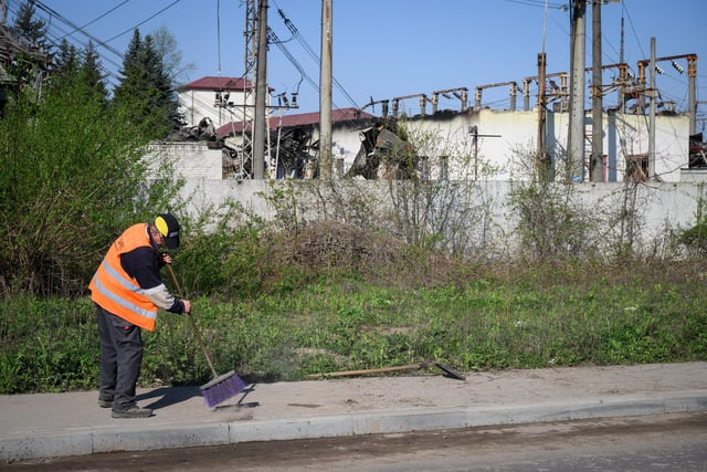 A street cleaner sweeps the pavement outside an electricity substation Photo by Leon Neal/Getty Images
