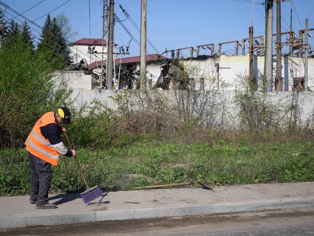 A street cleaner sweeps the pavement outside an electricity substation Photo by Leon Neal/Getty Images