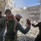 A man carries a young bombing casualty to safety after a reported air strike by Syrian regime forces or their allies on the jihadist-held town of Maaret Al-Noman in 2019 (Picture: Abdulaziz Ketaz/AFP via Getty Images)
