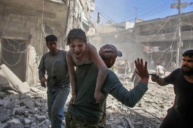A man carries a young bombing casualty to safety after a reported air strike by Syrian regime forces or their allies on the jihadist-held town of Maaret Al-Noman in 2019 (Picture: Abdulaziz Ketaz/AFP via Getty Images)
