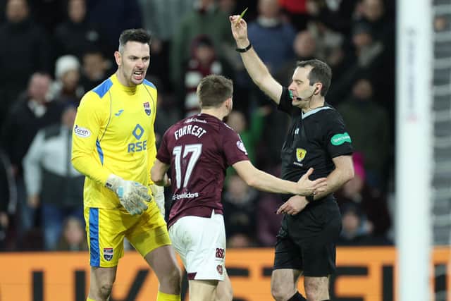 Referee Alan Muir shows Hearts' Alan Forrest a yellow card during the match against Ross County.