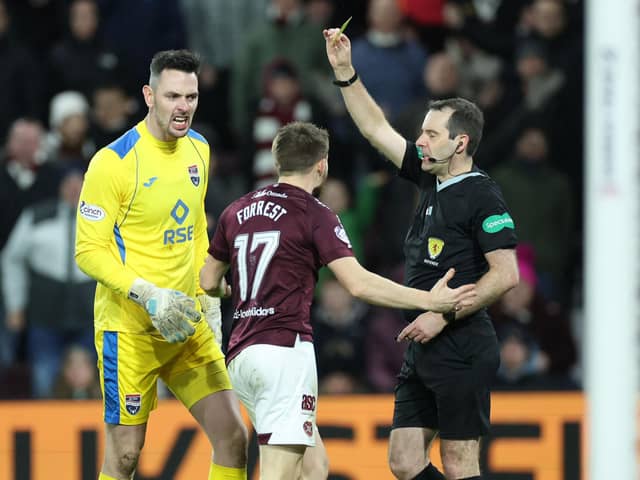 Referee Alan Muir shows Hearts' Alan Forrest a yellow card during the match against Ross County.