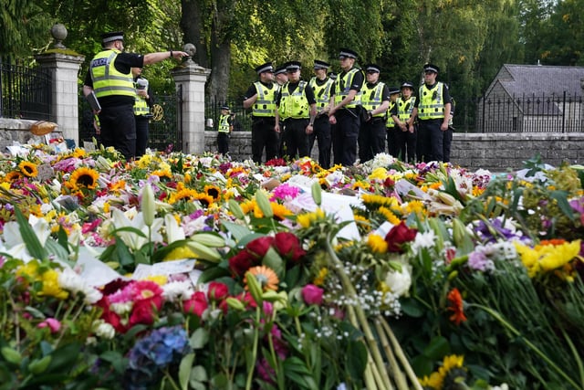 Police officers arrive at the gates of Balmoral where flowers and tributes have been laid by members of the public (Pic: PA/Andrew Milligan)
