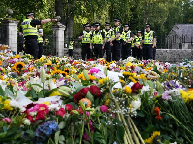 Police officers arrive at the gates of Balmoral where flowers and tributes have been laid by members of the public (Pic: PA/Andrew Milligan)