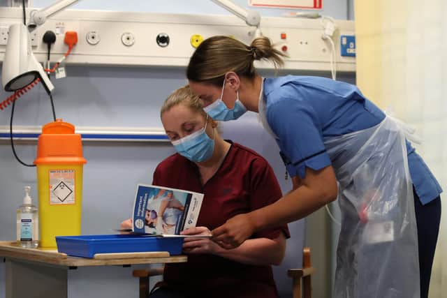 Deputy charge nurse Katie McIntosh(r) goes through leaflets with Clinical Nurse Manager Medicine Suzanne Dillon as the first of two Pfizer/BioNTech Covid-19 vaccine jabs are being given to staff at the Western General Hospital, in Edinburgh on December 8.