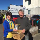 Chris Anne Campbell, from NHS Western Isles health board, takes delivery of the first batch of special visors from Tony Robson, engineering consultant for community wind farm operator Point and Sandwick Trust