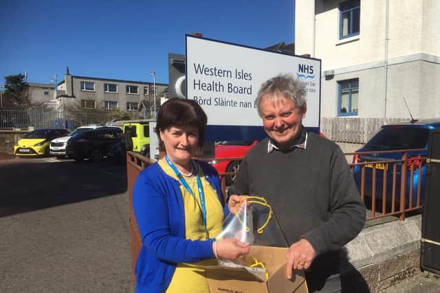 Chris Anne Campbell, from NHS Western Isles health board, takes delivery of the first batch of special visors from Tony Robson, engineering consultant for community wind farm operator Point and Sandwick Trust