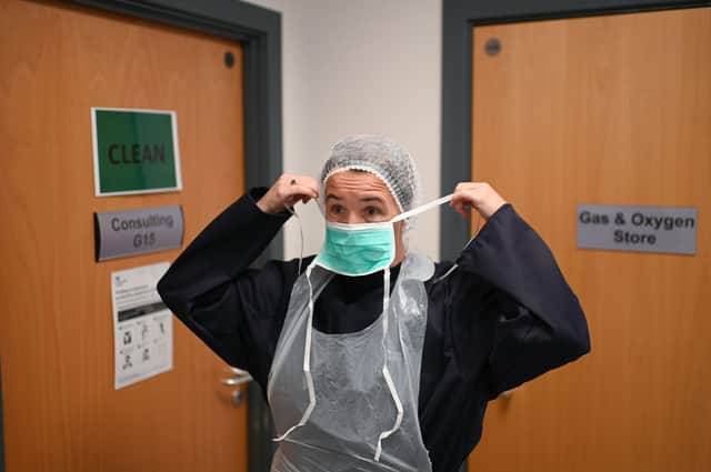 A doctor  dons personal protective equipment (PPE)