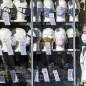 A woman wearing a protective face mask walks past a shop selling masks in Edinburgh city centre