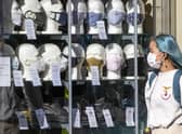 A woman wearing a protective face mask walks past a shop selling masks in Edinburgh city centre
