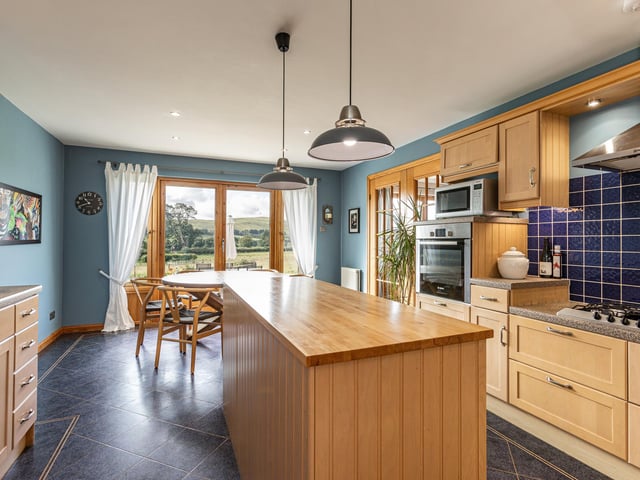 Interior: The house is entered via a rear veranda and all rooms are connected by a central hallway. The lounge offers bucolic views from its large windows and an open-plan kitchen-diner has doors opening to the garden. Two bedrooms are on the ground level and two are upstairs.